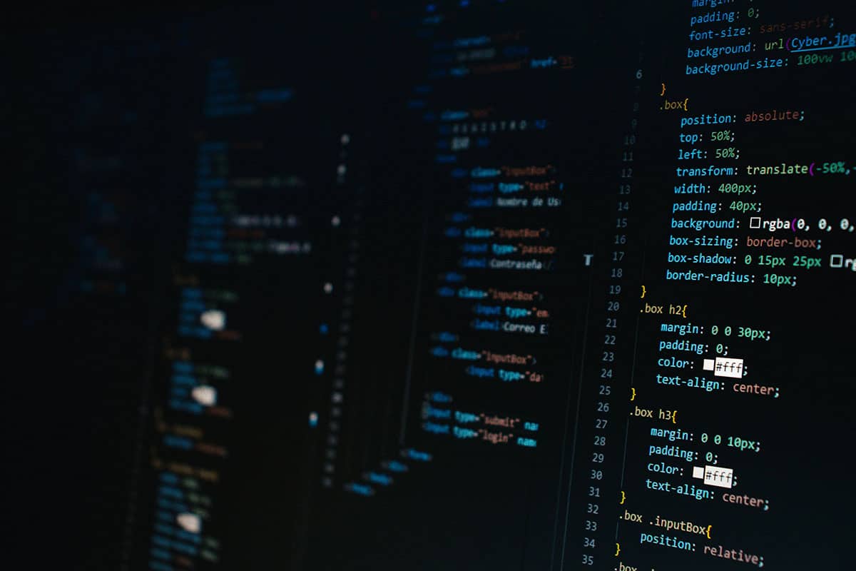 Skjerm med mørkt grensesnitt og synlig kildekode i et serverrom